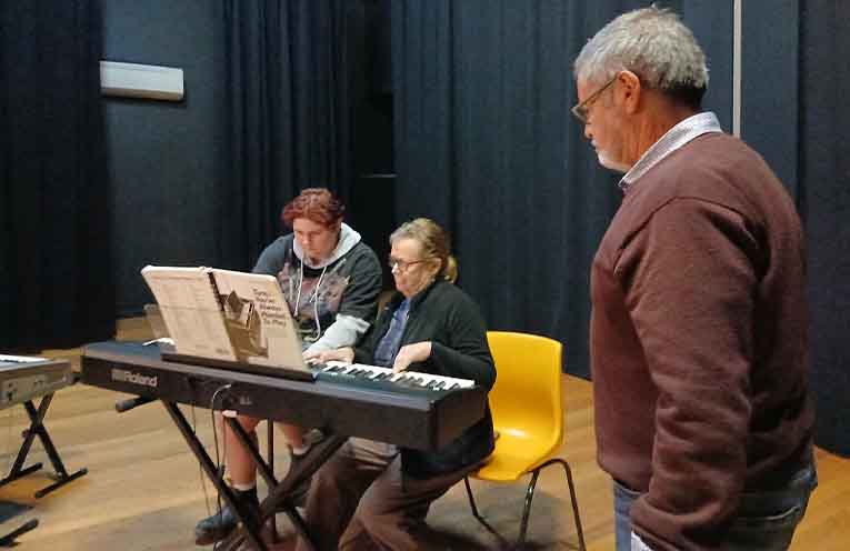 On-stage local musician Peter Smith watches a piano duet performance.