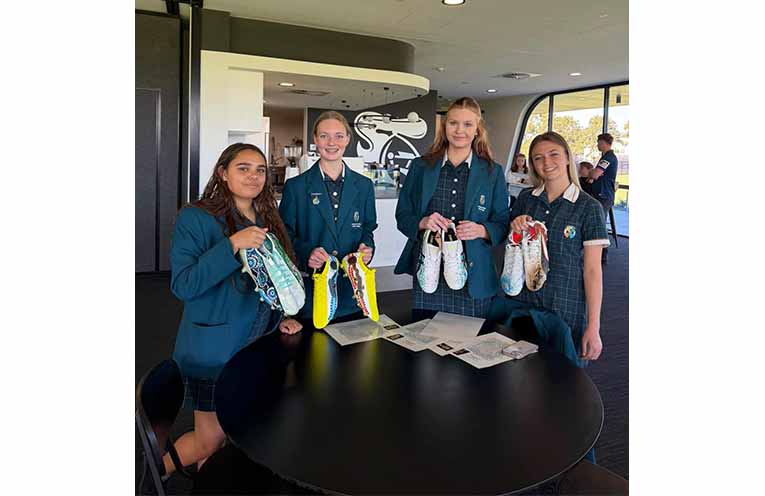 Students present Newcastle Knights players with hand-painted boots in honour of Indigenous Round. Photos: CMCC Facebook.